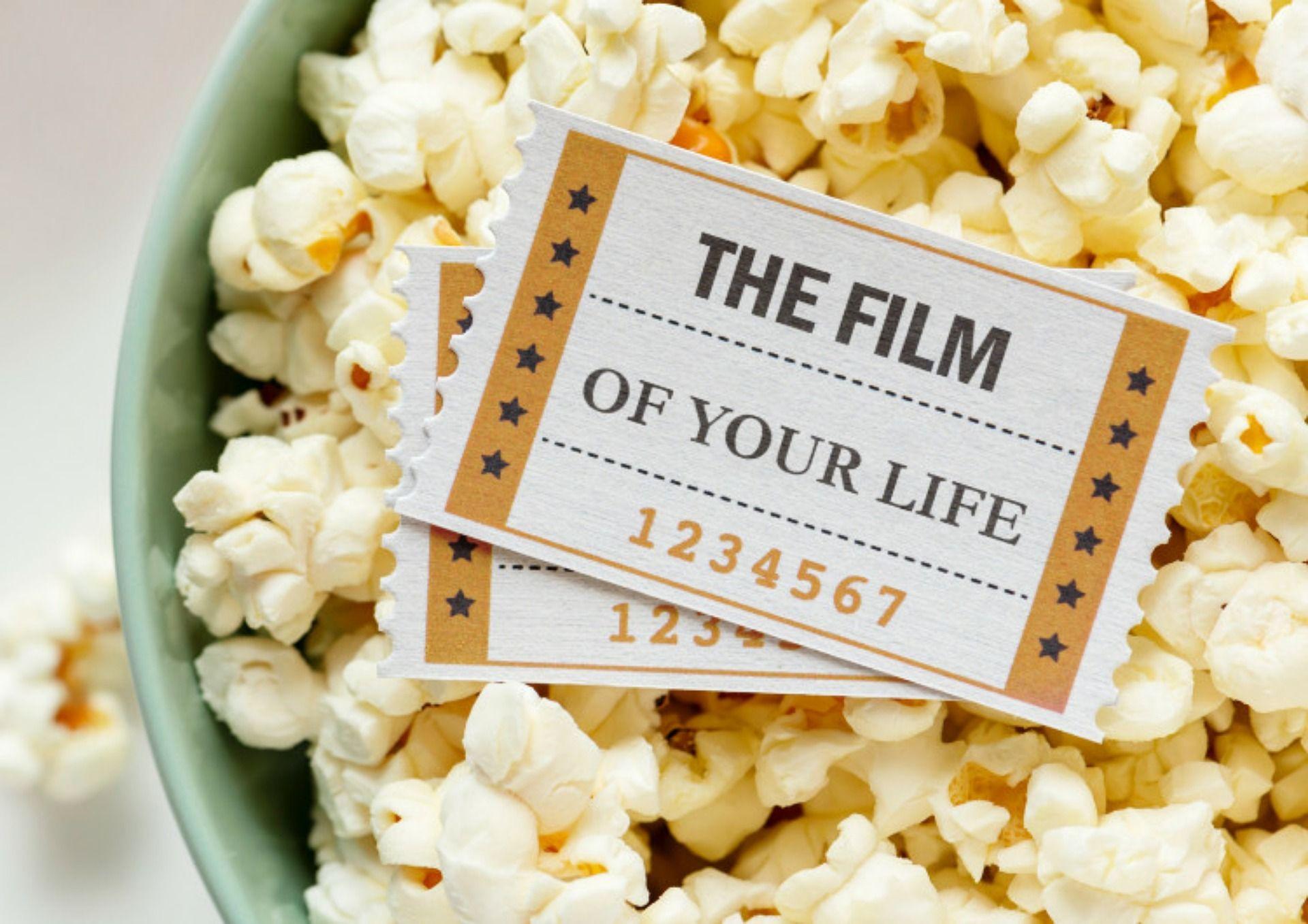 Popcorn in a bowl with two movie tickets reading 'THE FILM OF YOUR LIFE'.